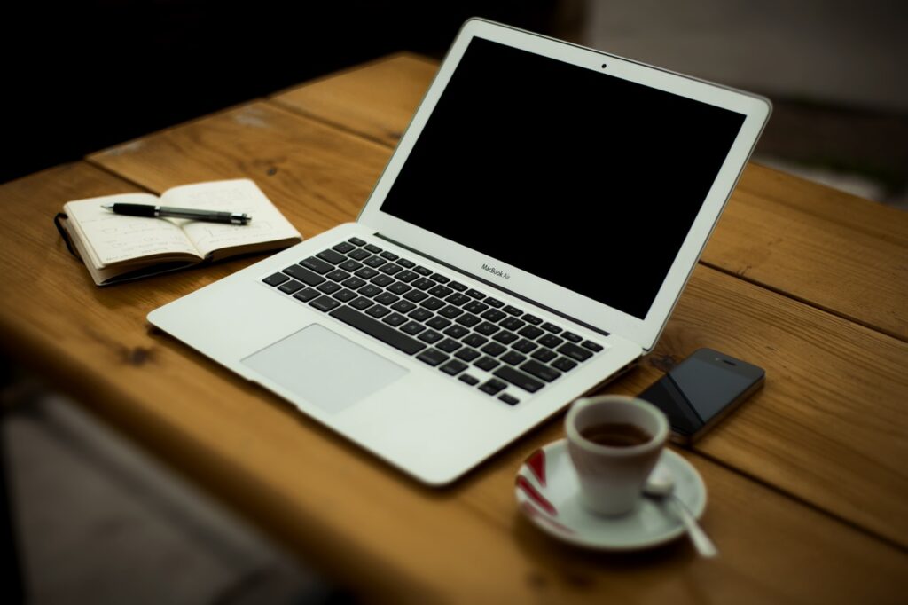 laptop next to open book and cup of coffee